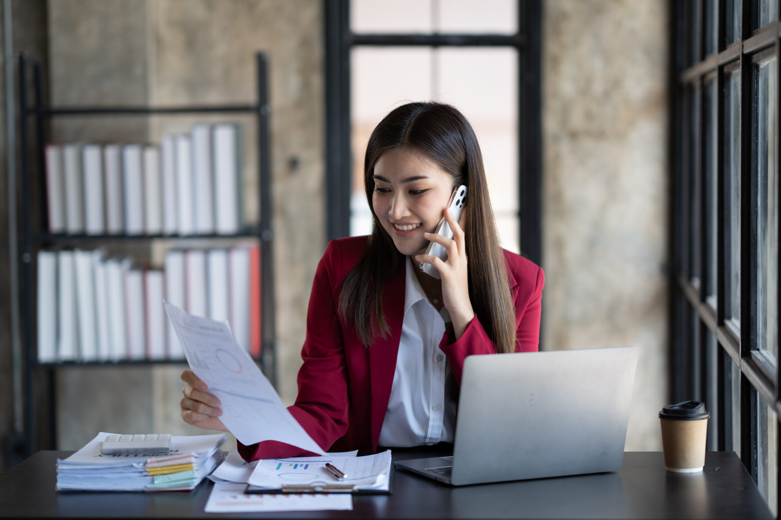 Happy businesswoman using mobile phone while working at office w
